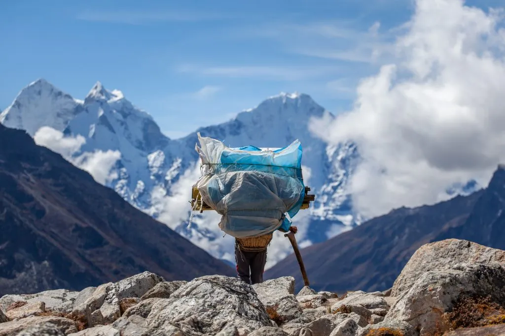 Nosič nesoucí těžký náklad na treku do základního tábora Everestu, Himálaj, Nepál